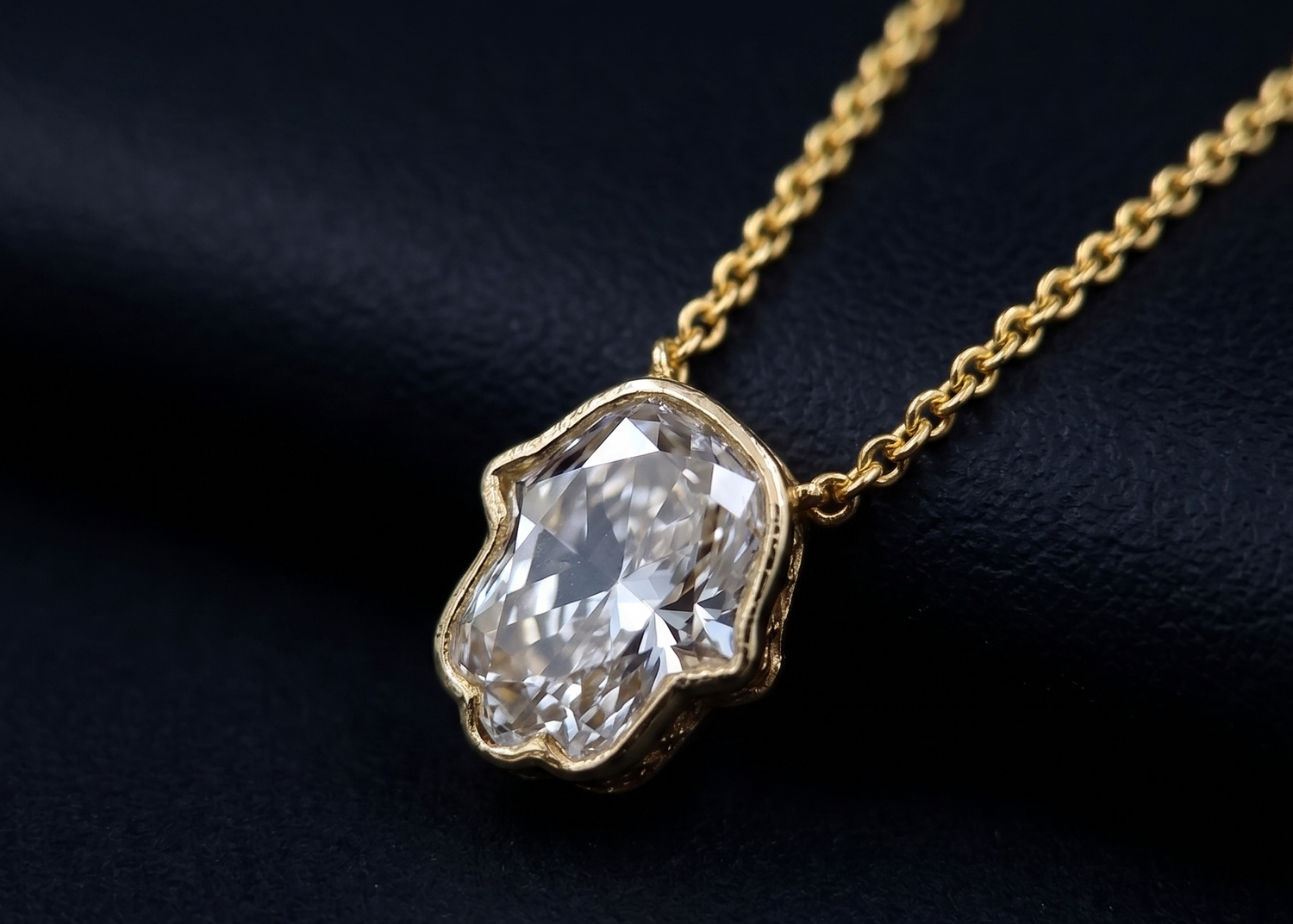 Gold necklace with a large diamond pendant on a dark background