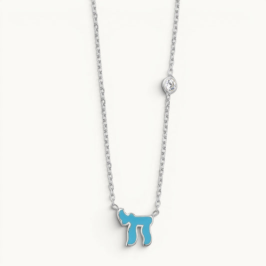 Chai Hebrew necklace in sterling silver or gold plated, featuring a pink or blue gemstone, symbolizing life and faith.