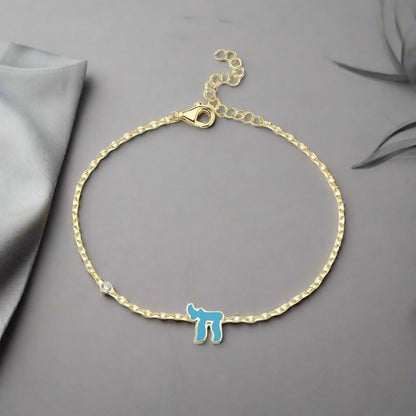 Chai Hebrew bracelet in sterling silver or 14k gold, featuring a pink or blue gemstone, symbolizing life and faith.