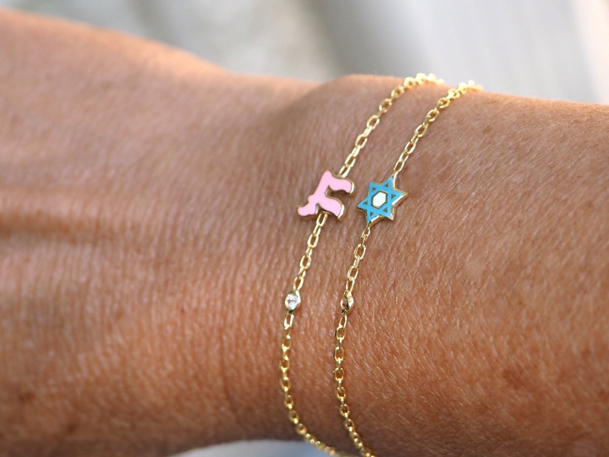 A stunning Chai Hebrew bracelet in sterling silver or gold, featuring a sparkling pink or blue gemstone and a meaningful life symbol.