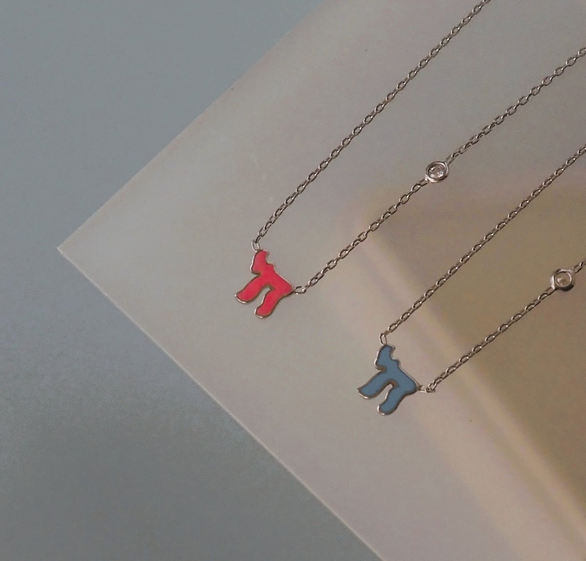 Chai Hebrew necklace in sterling silver or 14k gold, featuring a sparkling pink or blue gemstone, a meaningful Bat Mitzvah gift.