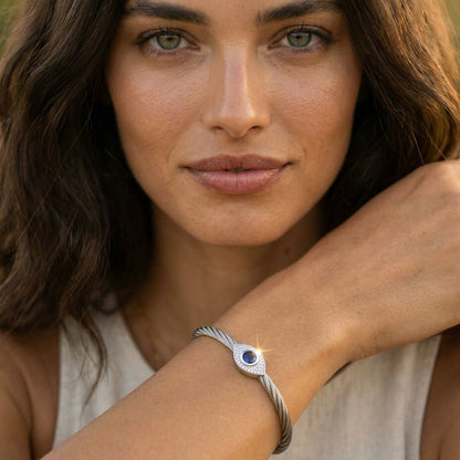 Evil eye bangle bracelet in yellow gold showcasing sapphire center stone and diamond halo by Alef Bet