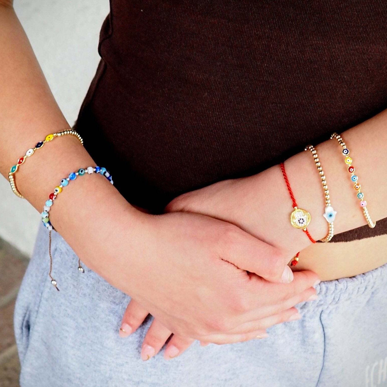 Two people holding hands with colorful bracelets on a blurred background