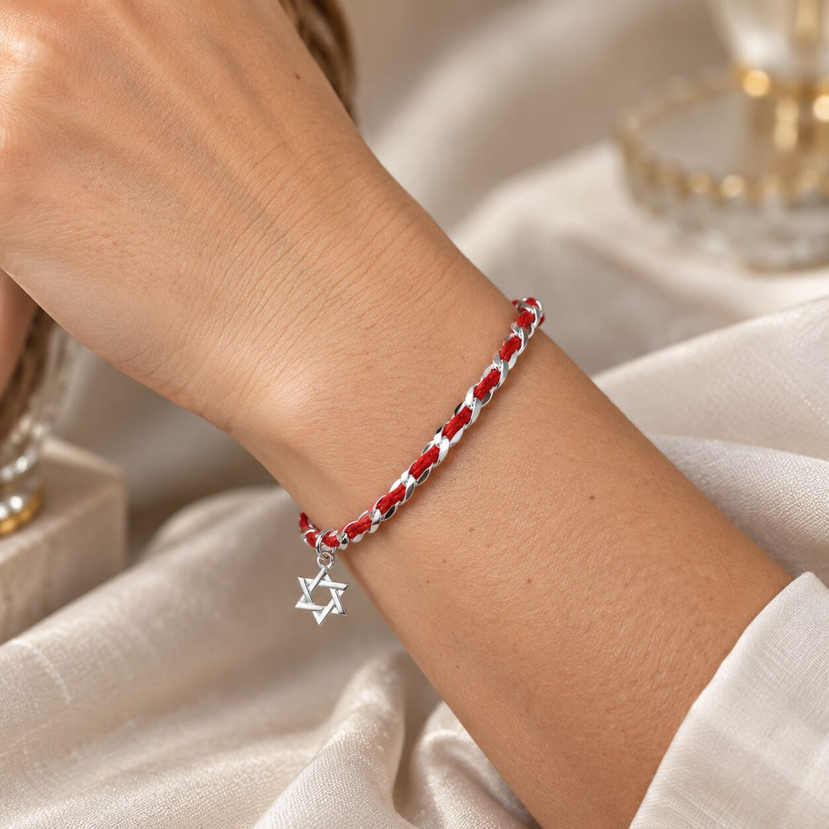 A red string of fate bendel bracelet with a sterling silver Star of David charm symbolizes protection within the Jewish faith.
