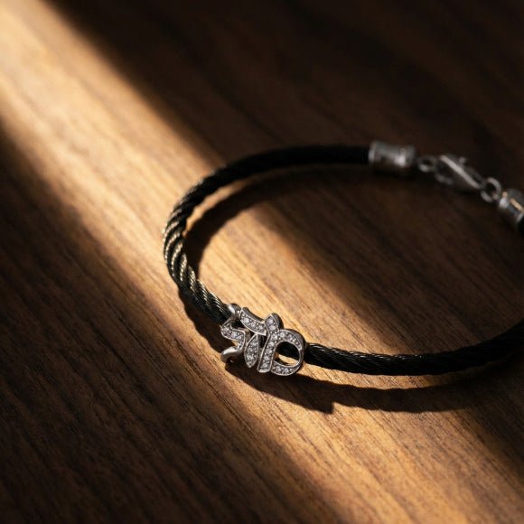 Gold-filled Mazel script bracelet on blue linen, representing the Hebrew meaning of luck and destiny.