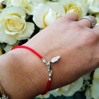 A stylish hamsa charm bracelet featuring a protective red string, made of durable sterling silver, perfect for everyday wear.