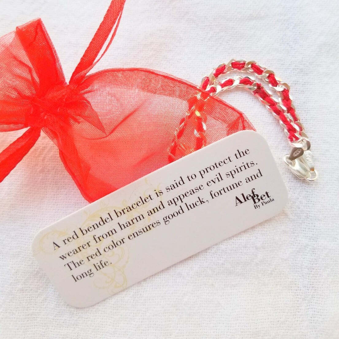 A durable sterling silver hamsa charm bracelet with a red string, symbolizing protection, comes gift-wrapped and includes a story card.