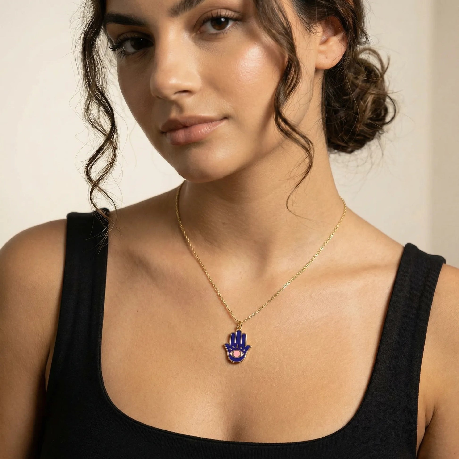Gold plated hamsa pendant necklace featuring navy enamel and pink evil eye detail by Alef Bet