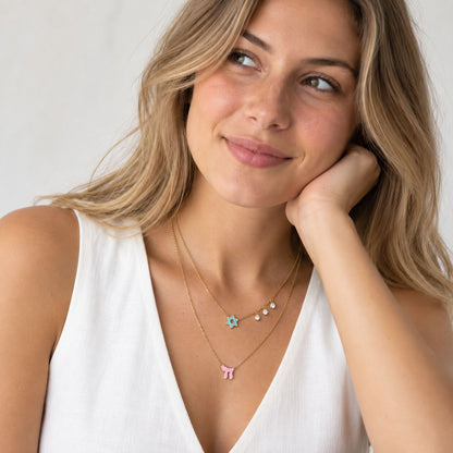 A layered necklace featuring a pink Star of David and Chai charms, accented with diamond-like gems for a timeless look.