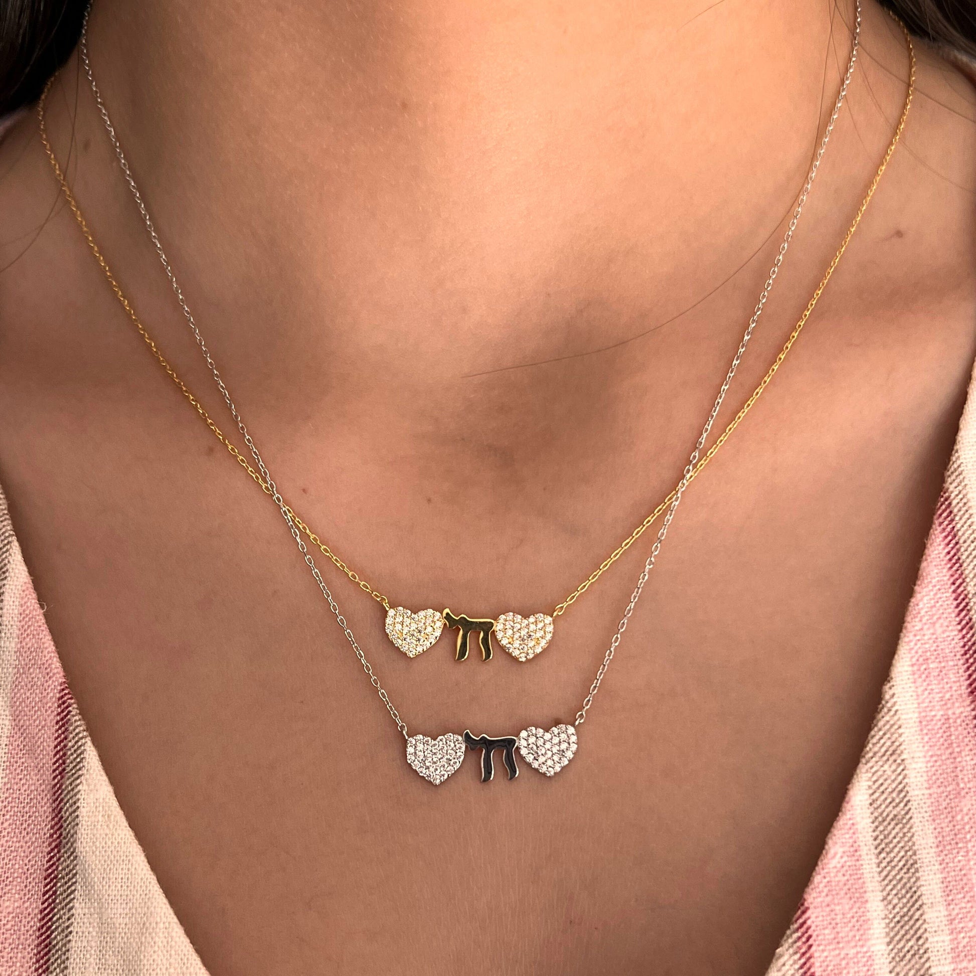 Silver necklace featuring two hearts and a Chai symbol, adorned with CZ gems, adjustable chain 16" to 18", representing love and life.