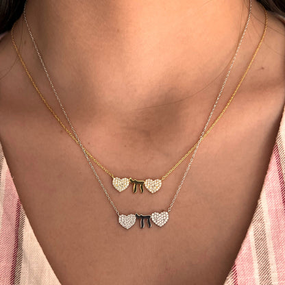 Silver necklace featuring two hearts and a Chai symbol, adorned with CZ gems, adjustable chain 16" to 18", representing love and life.