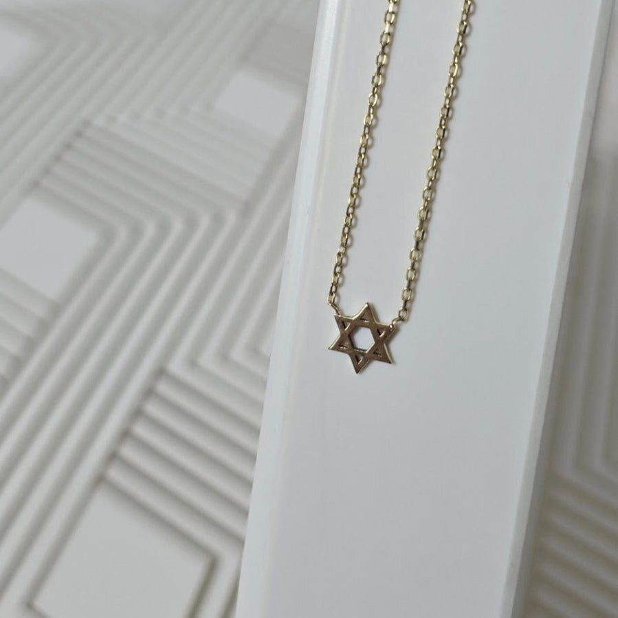 Gold necklace with a star pendant on a white background
