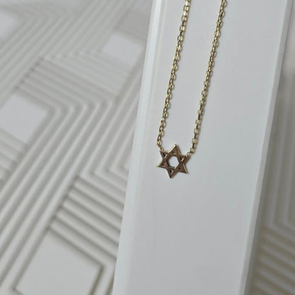 Gold necklace with a star pendant on a white background