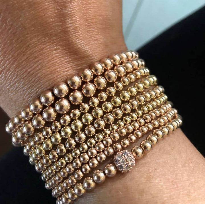 arm display of bead bracelets in rose and yellow gold